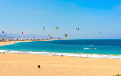 Plage dorée et calme en Algarve, mer turquoise et cerfs-volants au loin, horizon clair et horizon azur. Location villa de luxe portugal est suggérée par le contexte.