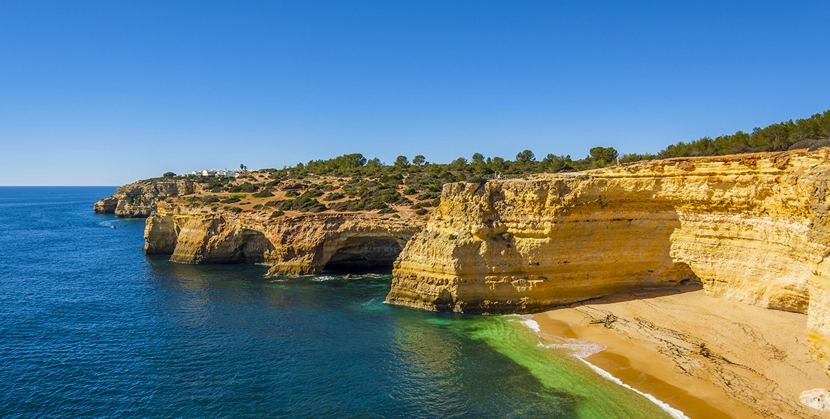 falaise côtière dorée surplombant une mer bleue azur, plage de sable; paysage de l’Algarve Portugal pour une location Algarve Portugal