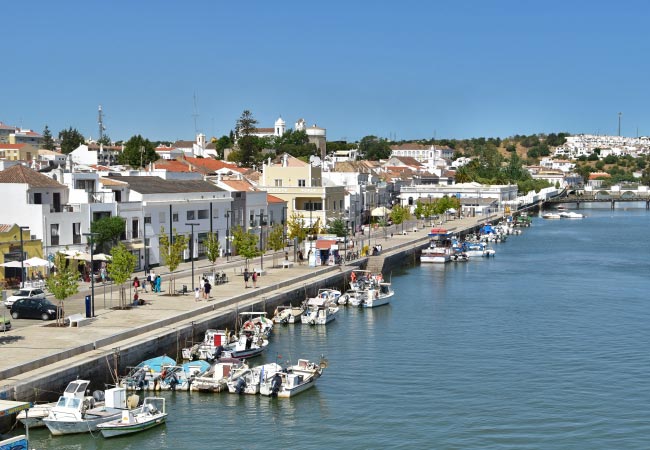 Quaint Tavira riverside along the eastern Algarve, boats moored by a sunny waterfront street