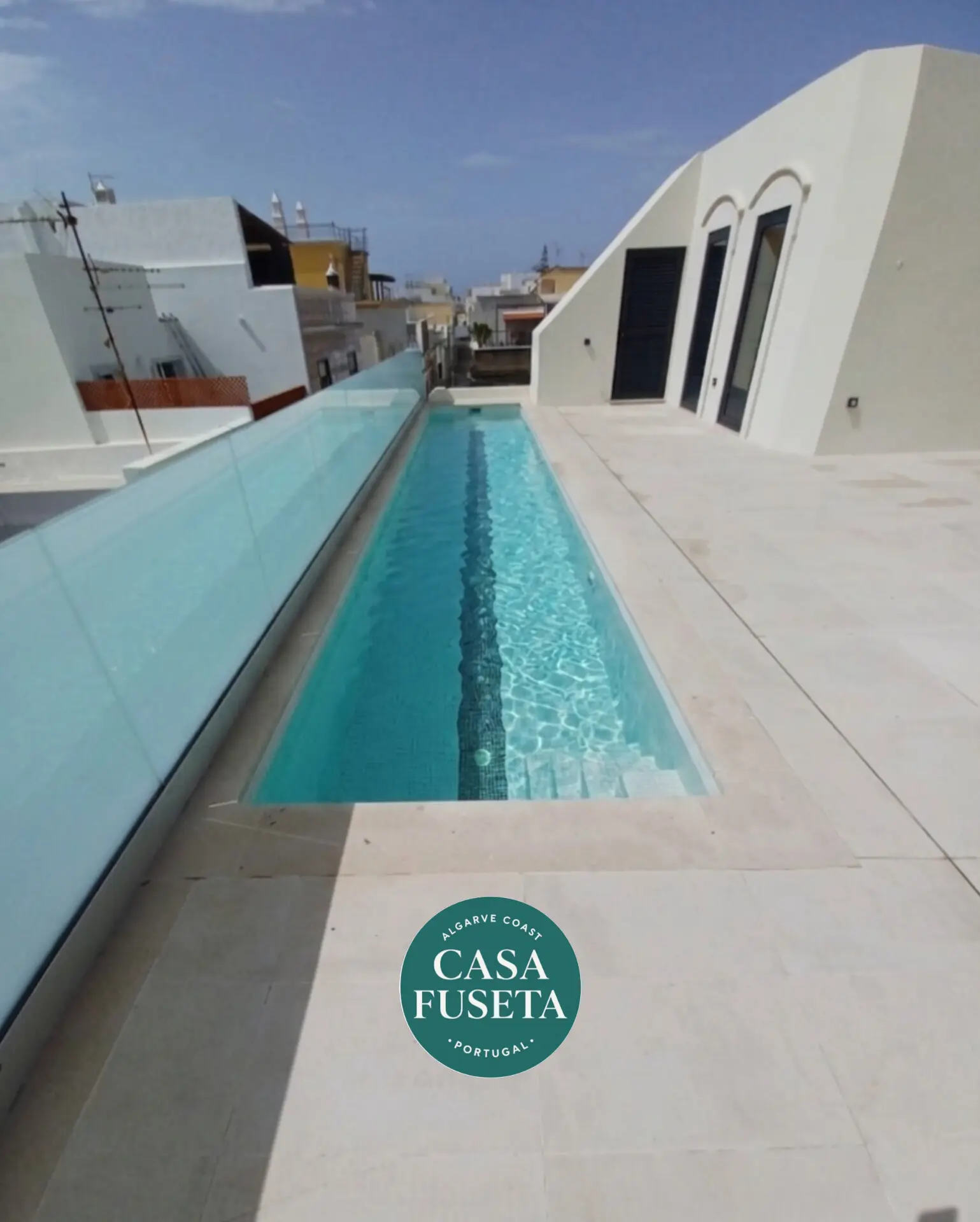 Piscine longue sur terrasse en bois avec vue urbaine, villa élégante et façade blanche; logo CASA FUSETA Algarve côte. alt: villa plage privée algarve? Include keyword naturally. Let's craft: "Villa plage privée Algarve : terrasse avec piscine longue et vue sur les toits, accès direct à la villa." But must describe visible image: rooftop terrace, pool, glass railing, white modern building. Include keyword integrated: "villa plage privée algarve". Let's produce: "Villa plage privée Algarve avec terrasse et longue piscine sur le toit, balustrade en verre et façade blanche moderne." Ensure 125 chars. Let's count: "Villa plage privée Algarve avec terrasse et longue piscine sur le toit, balustrade en verre et façade blanche moderne." That's around 125. Good. Also mention logo CASA FUSETA? Not necessary. Keep within 125. Let's output. But ensure not to claim more than visible. OK. Let's finalize.