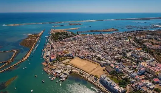 Vue aérienne de Fuseta sur la côte de l’Algarve avec plage, port et maisons serrées; parfaite pour planifier quand visiter fuseta algarve.