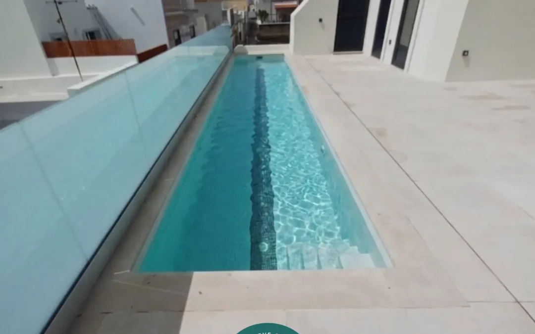Rooftop pool with clear water, glass railing, and white modern buildings; Casa Fuzeta logo on terrace, in Fuseta, Portugal. fuzeta vacation rental.
