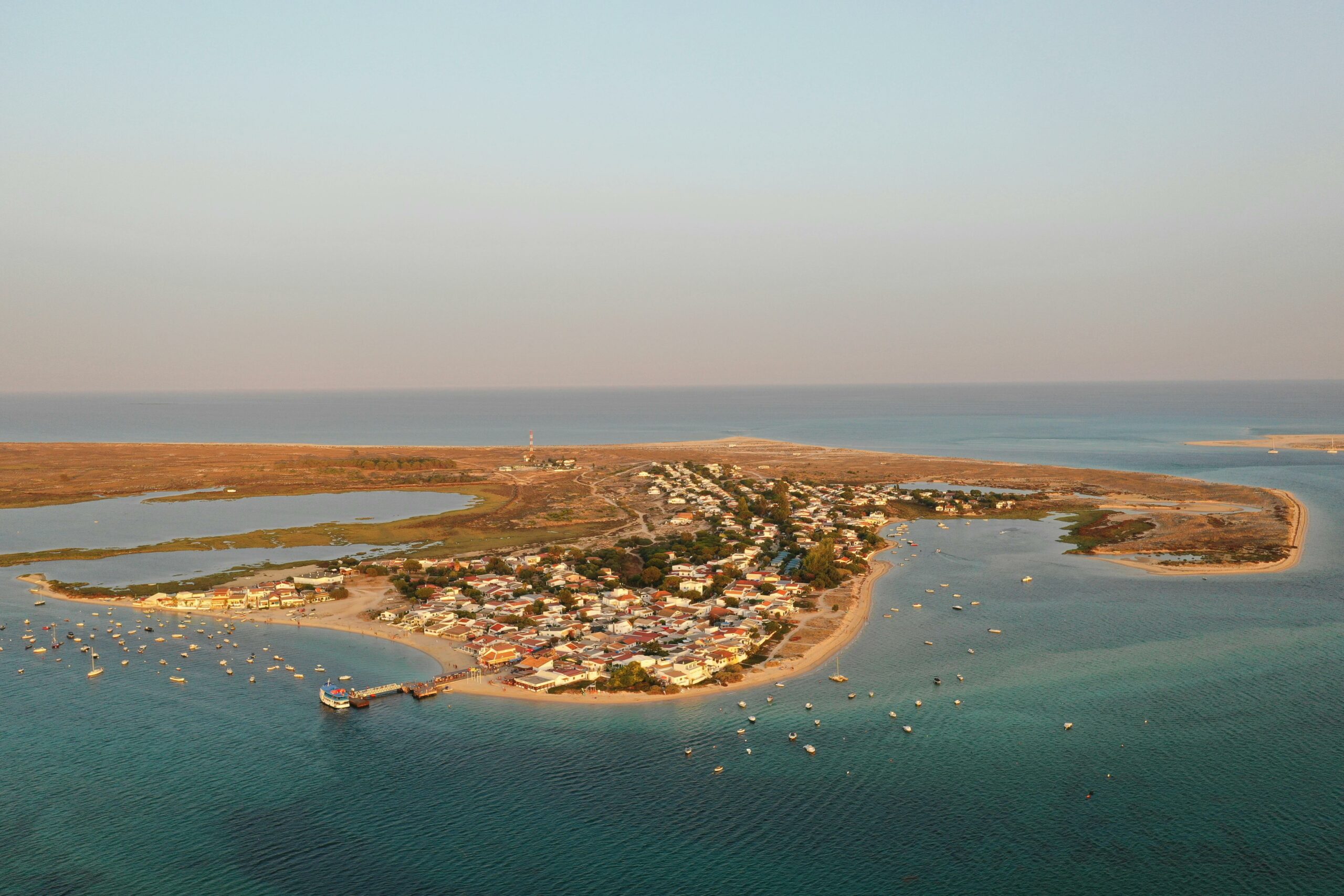 Vue aérienne d’un village de pêcheurs en Algarve, entouré par des eaux turquoise, port animé et vieilles maisons colorées. meilleures locations de charme dans un village de pecheurs en algarve ?