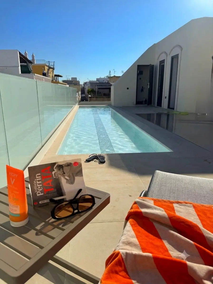 Rooftop pool area at Casa Fuzeta with glass balustrade, sun loungers, a bright sunlit deck, and sea views in the Algarve. A